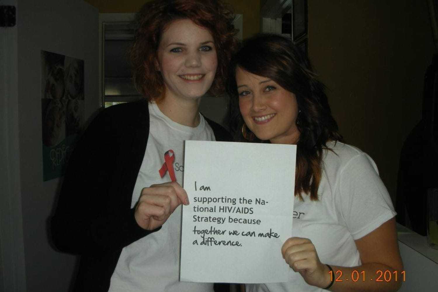 Two women holding a sign supporting the National HIV/AIDS Strategy.