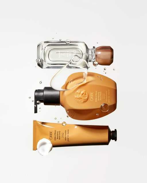 Oribe beauty products with stylish packaging and water droplets against a light background.